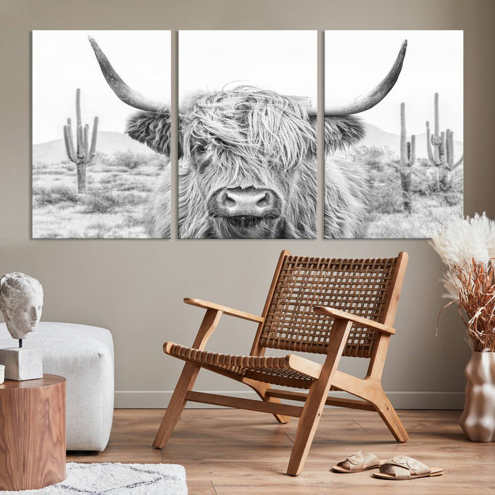 The "Rustic Charm | Cow Longhorn Black White Bighorn Wall Art Canvas Print" is a stunning triptych that showcases a highland cow with long horns set against a desert landscape with cacti in the background. This farmhouse wall art elevates any room into a rustic haven with its gallery-quality canvas.