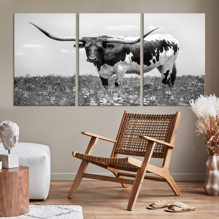 The Texas Black White Highland Longhorn Cow Wall Art Canvas Print, a gallery-quality triptych, elegantly adorns the wall, showcasing a striking black-and-white depiction of a longhorn cow in a field.