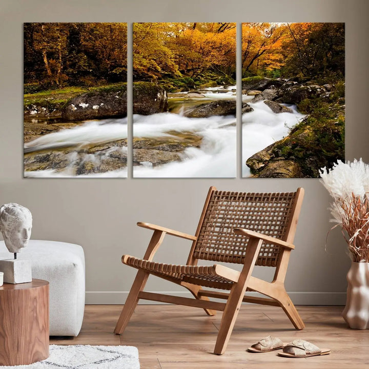 The living room is adorned with the "Wall Art Waterfall Canvas Print River in Forest in Autumn," a triptych on museum-quality canvas showcasing a flowing river surrounded by autumn trees. This ready-to-hang artwork features a UV-protective coating to ensure enduring vibrancy.