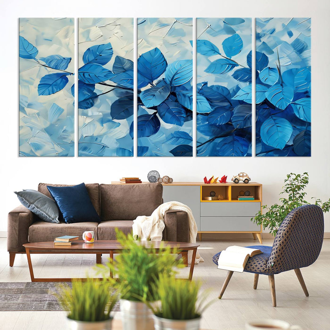 The contemporary living room is highlighted by the Abstract Blue Leaf Wall Art Canvas Print on the wall. The hand-assembled framed art enhances the room's vibrant decor, crafting a gallery-worthy ambience.