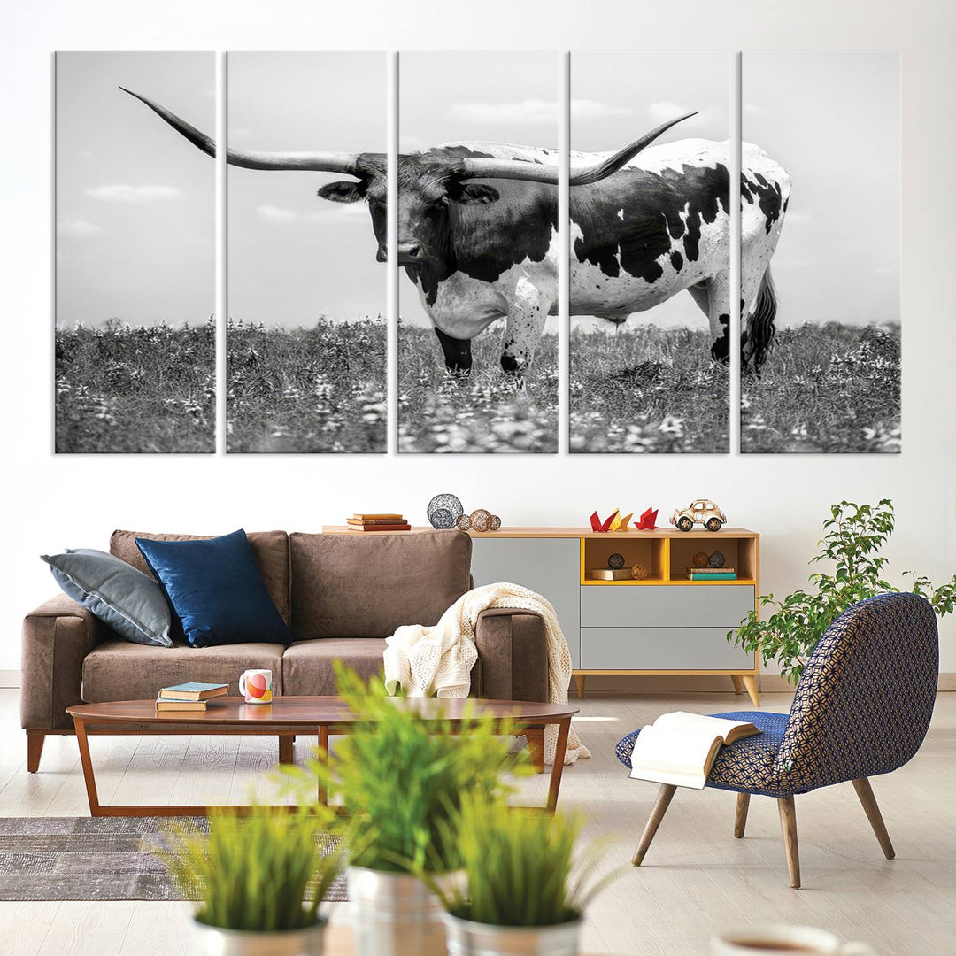 The Texas Black White Highland Longhorn Cow Wall Art Canvas Print, a gallery-quality triptych, elegantly adorns the wall, showcasing a striking black-and-white depiction of a longhorn cow in a field.