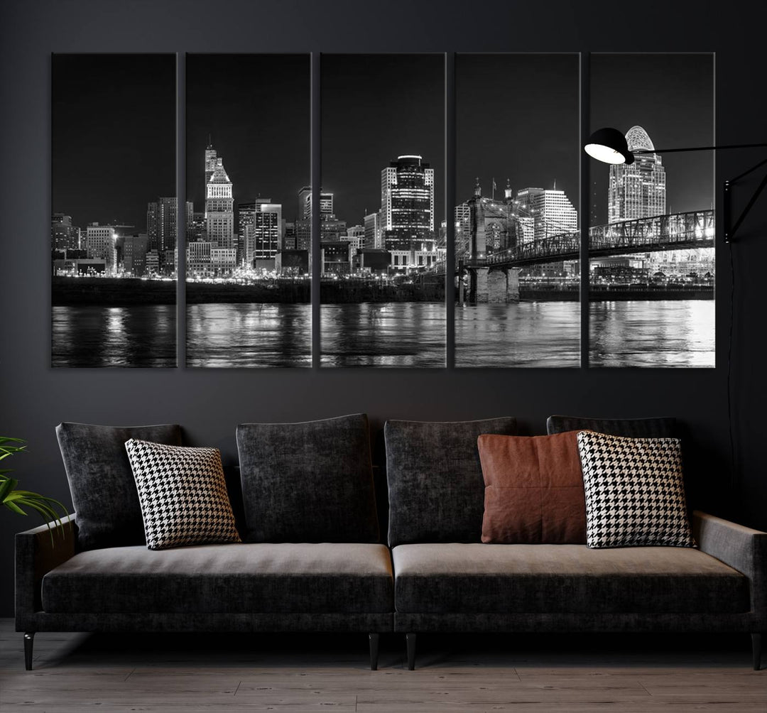 The Cincinnati City Lights Skyline Black and White Wall Art Cityscape Canvas Print elegantly adorns a modern living room. This museum-quality canvas triptych of a city skyline is enhanced by hand-assembled frames for added finesse, and you can enjoy free shipping on this stunning home addition.