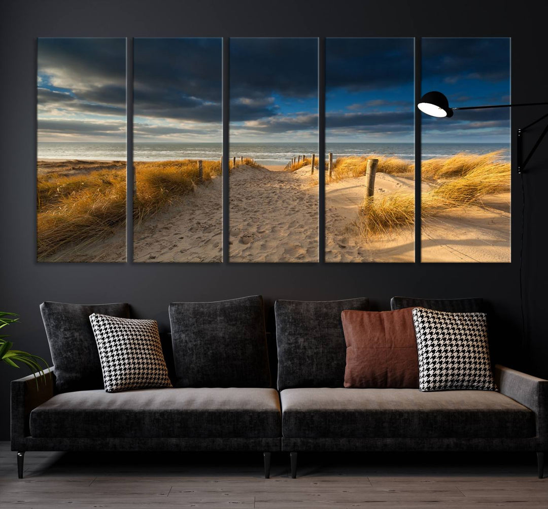 The Ocean Beach Dark Clouds Wall Art Canvas Print is a breathtaking triptych depicting a sandy beach path with tall grasses under an intense cloudy sky. It is crafted on museum-quality canvas with UV protection.