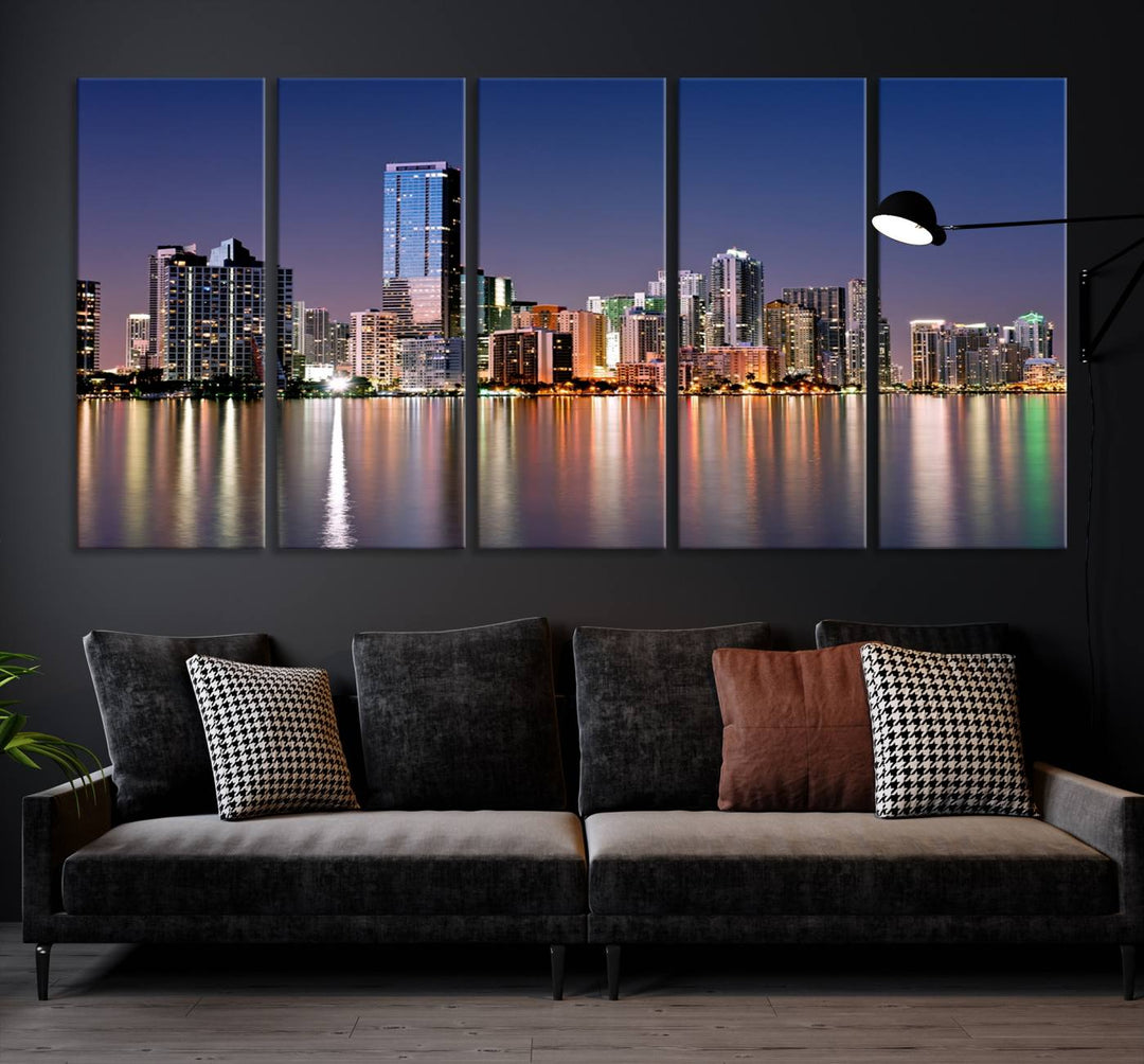 The Miami Skyline Canvas Wall Art Print showcases a vibrant night cityscape and beautifully captures the dazzling colorful lights reflecting on the water. This ready-to-hang triptych adorns the wall, creating a stunning visual centerpiece.