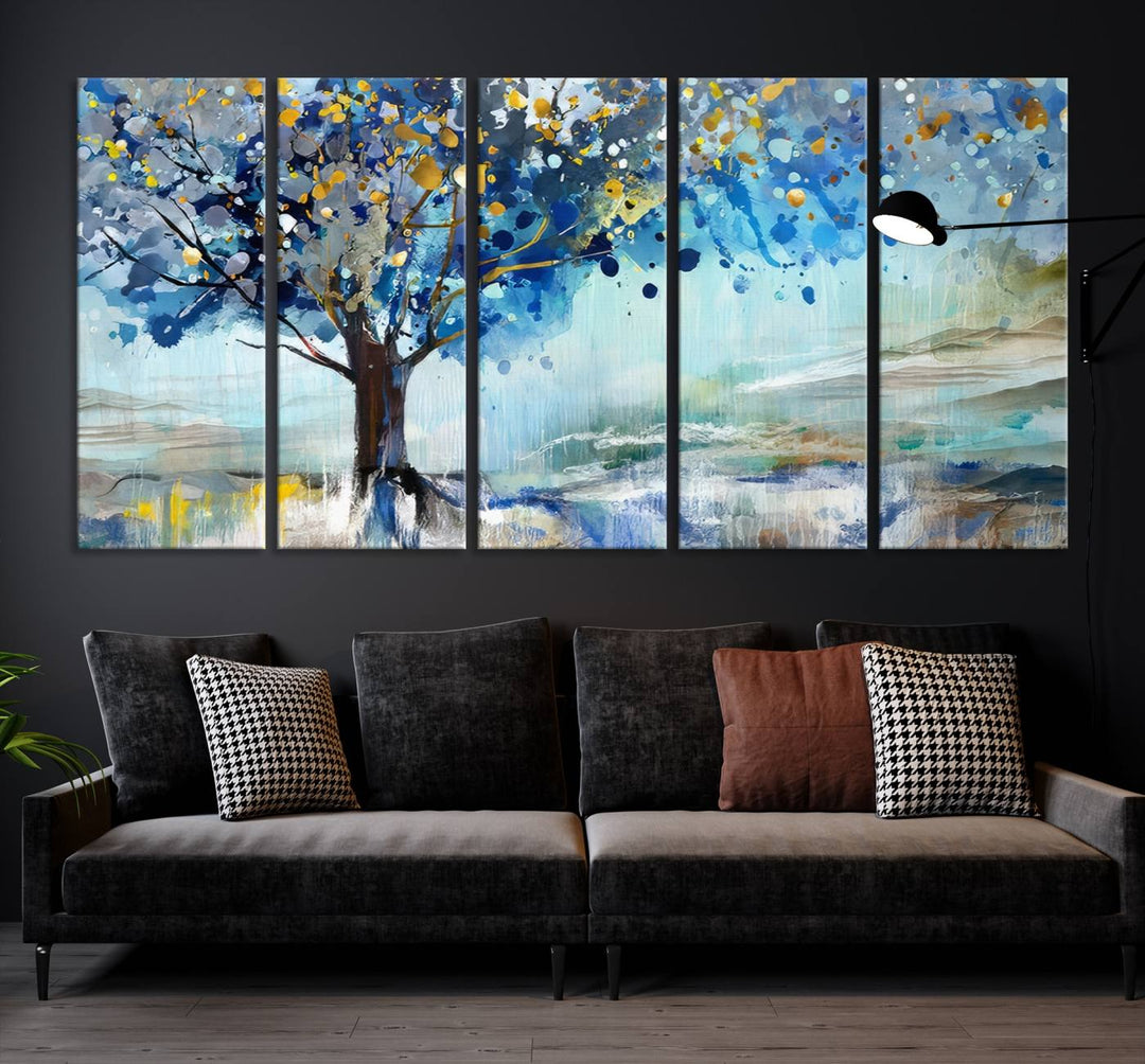 A modern living room features a three-panel Watercolor Style Abstract Tree Printing Wall Art Canvas in vibrant blue and yellow, crafted on museum-quality material.