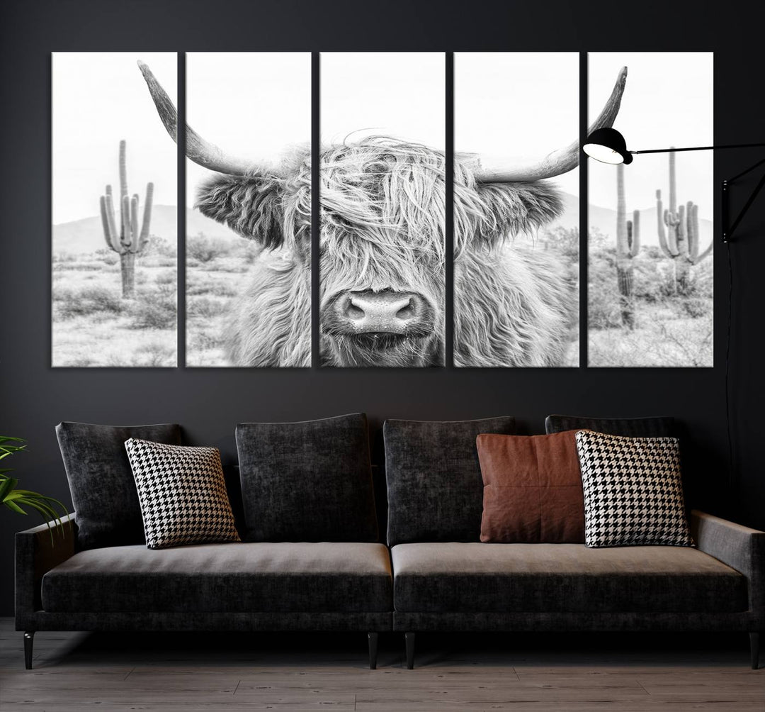 The "Rustic Charm | Cow Longhorn Black White Bighorn Wall Art Canvas Print" is a stunning triptych that showcases a highland cow with long horns set against a desert landscape with cacti in the background. This farmhouse wall art elevates any room into a rustic haven with its gallery-quality canvas.