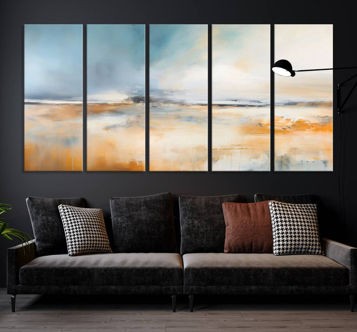 The Abstract Landscape Wall Art Canvas Print, featuring warm tones of orange and blue, is displayed on a dark wall.