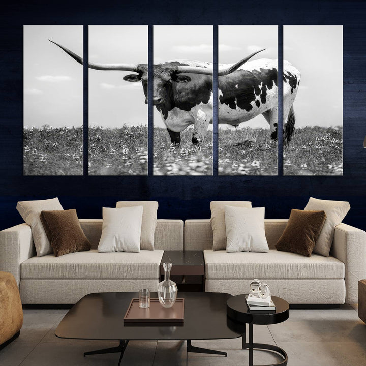 The Texas Black White Highland Longhorn Cow Wall Art Canvas Print, a gallery-quality triptych, elegantly adorns the wall, showcasing a striking black-and-white depiction of a longhorn cow in a field.