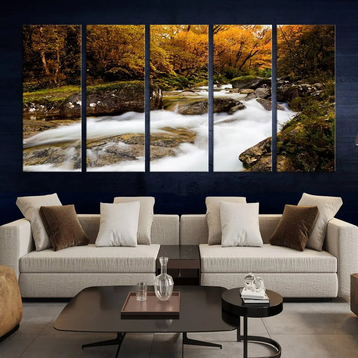 The living room is adorned with the "Wall Art Waterfall Canvas Print River in Forest in Autumn," a triptych on museum-quality canvas showcasing a flowing river surrounded by autumn trees. This ready-to-hang artwork features a UV-protective coating to ensure enduring vibrancy.