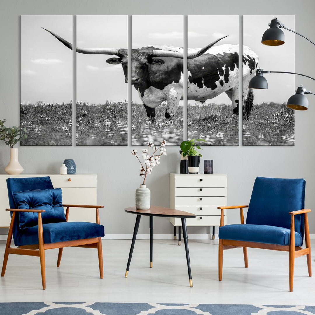 The Texas Black White Highland Longhorn Cow Wall Art Canvas Print, a gallery-quality triptych, elegantly adorns the wall, showcasing a striking black-and-white depiction of a longhorn cow in a field.