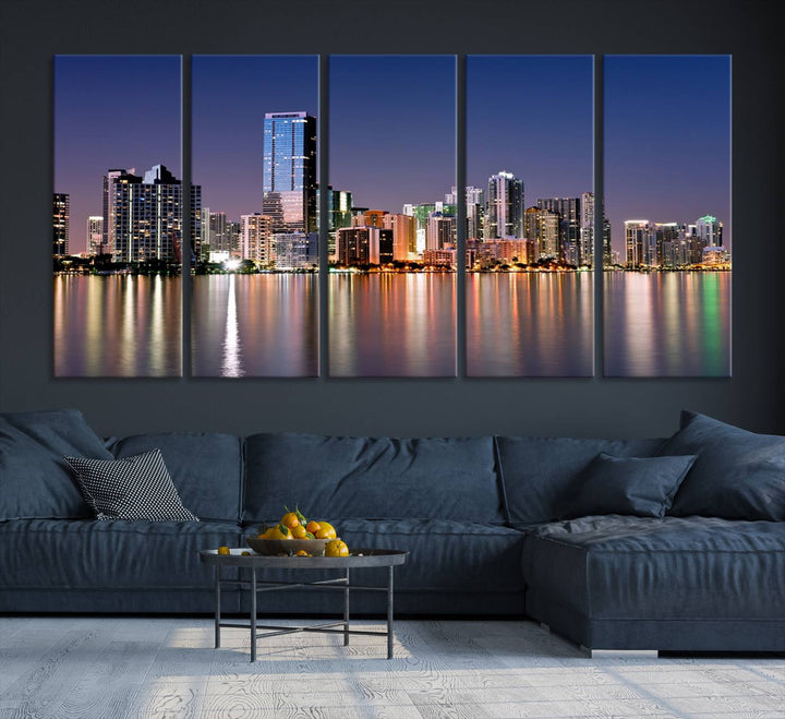 The Miami Skyline Canvas Wall Art Print showcases a vibrant night cityscape and beautifully captures the dazzling colorful lights reflecting on the water. This ready-to-hang triptych adorns the wall, creating a stunning visual centerpiece.