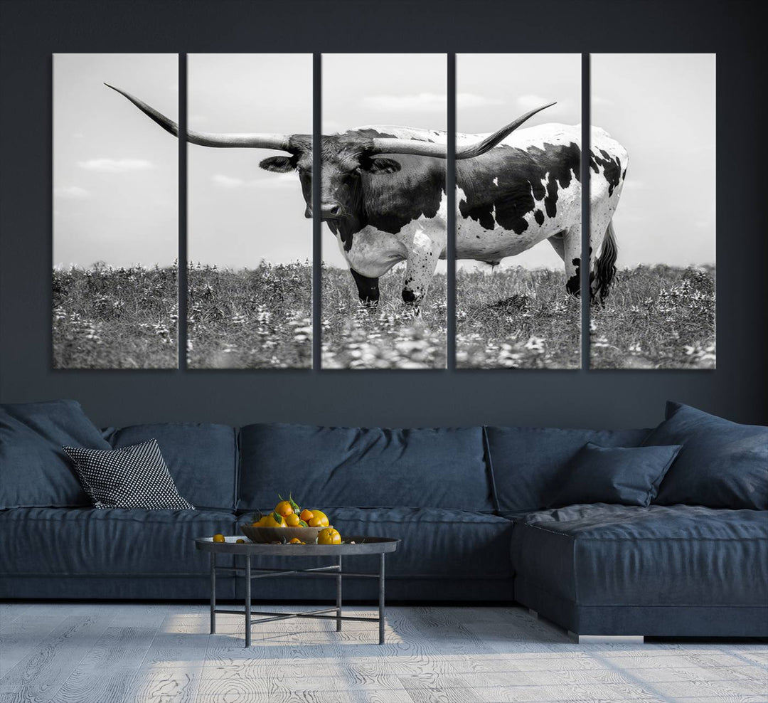 The Texas Black White Highland Longhorn Cow Wall Art Canvas Print, a gallery-quality triptych, elegantly adorns the wall, showcasing a striking black-and-white depiction of a longhorn cow in a field.