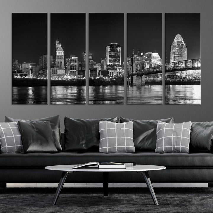 The Cincinnati City Lights Skyline Black and White Wall Art Cityscape Canvas Print elegantly adorns a modern living room. This museum-quality canvas triptych of a city skyline is enhanced by hand-assembled frames for added finesse, and you can enjoy free shipping on this stunning home addition.