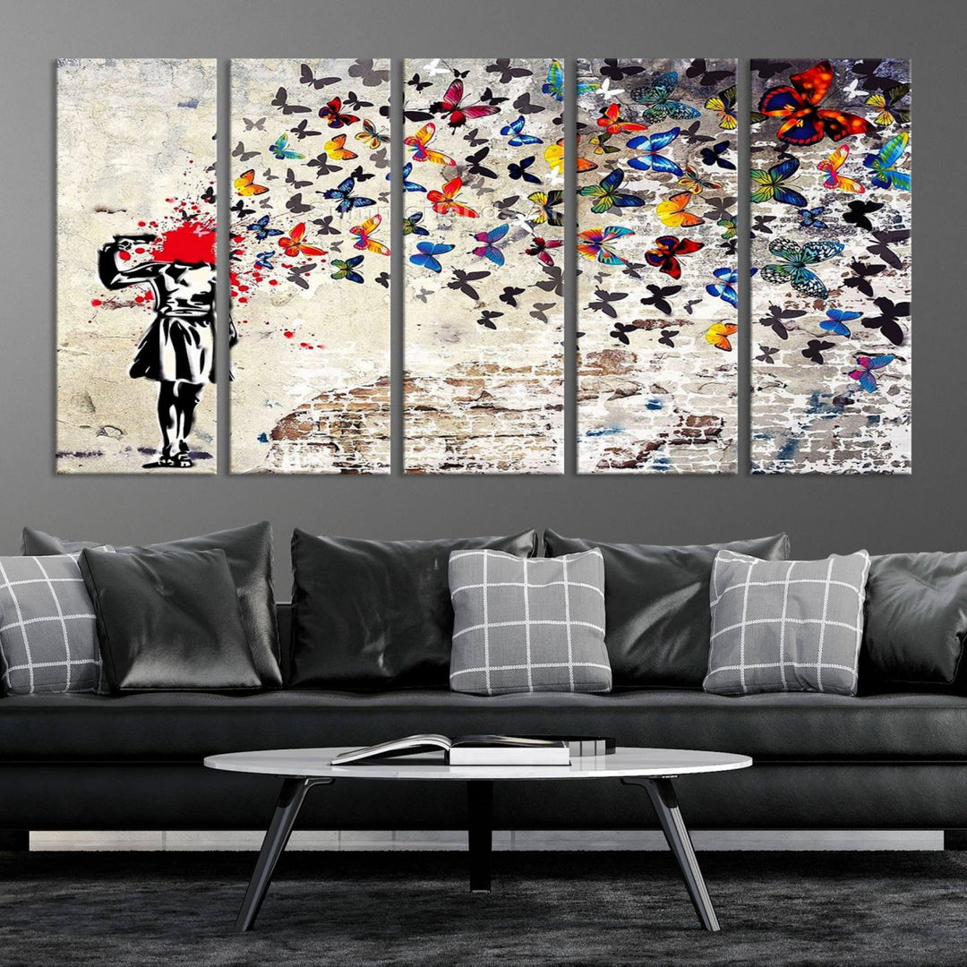 The Banksy Art Butterfly Girl Explosion Canvas showcases a dynamic figure with butterflies bursting from their head, set against a textured wall background. This vibrant urban graffiti piece is perfect for modern interiors and comes ready to hang.