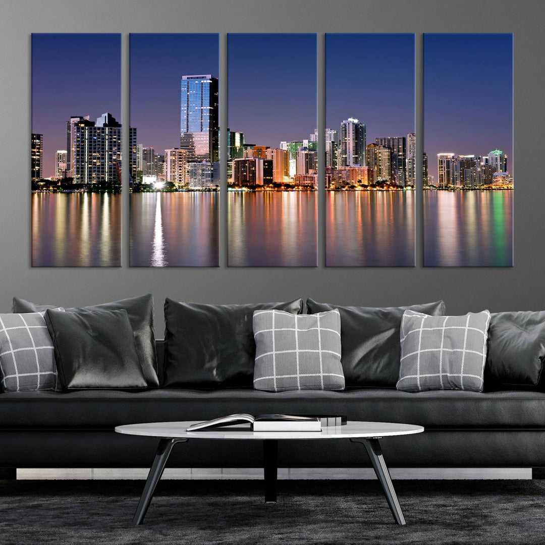 The Miami Skyline Canvas Wall Art Print showcases a vibrant night cityscape and beautifully captures the dazzling colorful lights reflecting on the water. This ready-to-hang triptych adorns the wall, creating a stunning visual centerpiece.