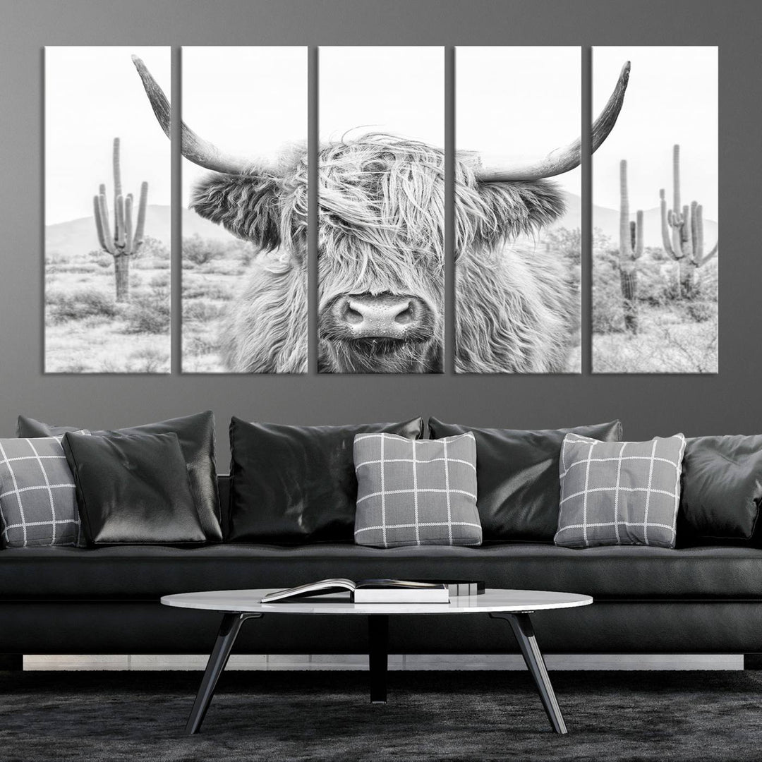 The "Rustic Charm | Cow Longhorn Black White Bighorn Wall Art Canvas Print" is a stunning triptych that showcases a highland cow with long horns set against a desert landscape with cacti in the background. This farmhouse wall art elevates any room into a rustic haven with its gallery-quality canvas.