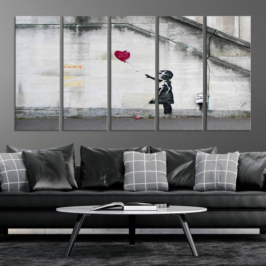 The "Girl with a Balloon Banksy Street Graffiti Art Canvas Print" is a gallery-quality wall art piece that features an image of a girl releasing a heart-shaped balloon. Handmade in the USA, this canvas artwork brings charm and emotion to any room.