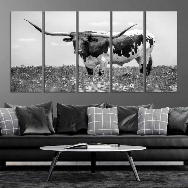 The Texas Black White Highland Longhorn Cow Wall Art Canvas Print, a gallery-quality triptych, elegantly adorns the wall, showcasing a striking black-and-white depiction of a longhorn cow in a field.