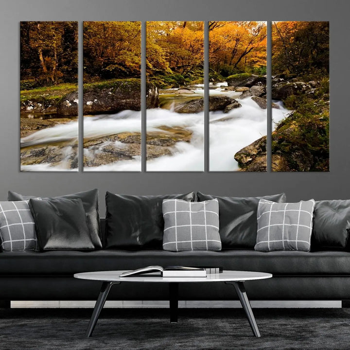 The living room is adorned with the "Wall Art Waterfall Canvas Print River in Forest in Autumn," a triptych on museum-quality canvas showcasing a flowing river surrounded by autumn trees. This ready-to-hang artwork features a UV-protective coating to ensure enduring vibrancy.