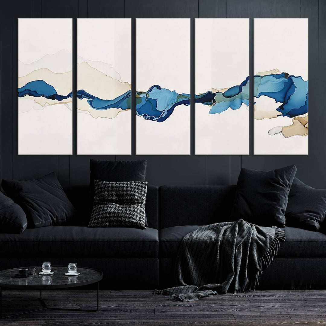 The modern living room showcases a set of three canvas prints with abstract blue art on museum-quality materials.