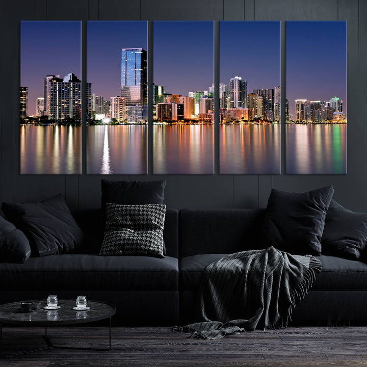 The Miami Skyline Canvas Wall Art Print showcases a vibrant night cityscape and beautifully captures the dazzling colorful lights reflecting on the water. This ready-to-hang triptych adorns the wall, creating a stunning visual centerpiece.