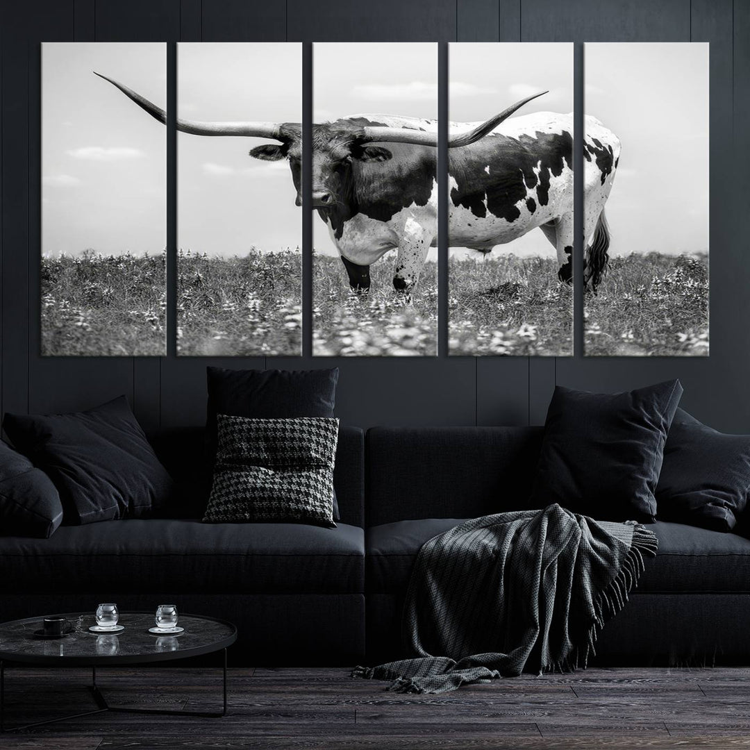 The Texas Black White Highland Longhorn Cow Wall Art Canvas Print, a gallery-quality triptych, elegantly adorns the wall, showcasing a striking black-and-white depiction of a longhorn cow in a field.