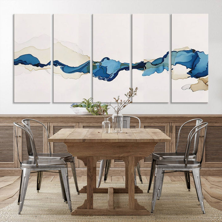 The modern living room showcases a set of three canvas prints with abstract blue art on museum-quality materials.