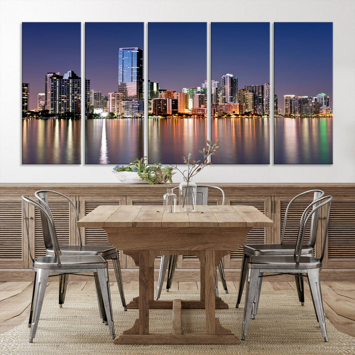 The Miami Skyline Canvas Wall Art Print showcases a vibrant night cityscape and beautifully captures the dazzling colorful lights reflecting on the water. This ready-to-hang triptych adorns the wall, creating a stunning visual centerpiece.