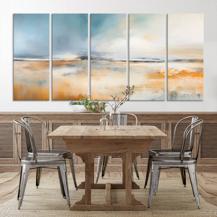 The Abstract Landscape Wall Art Canvas Print, featuring warm tones of orange and blue, is displayed on a dark wall.