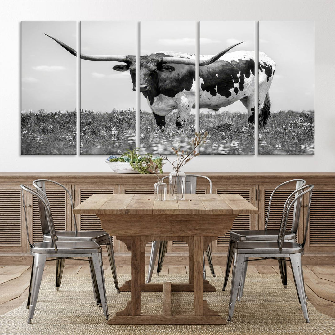 The Texas Black White Highland Longhorn Cow Wall Art Canvas Print, a gallery-quality triptych, elegantly adorns the wall, showcasing a striking black-and-white depiction of a longhorn cow in a field.