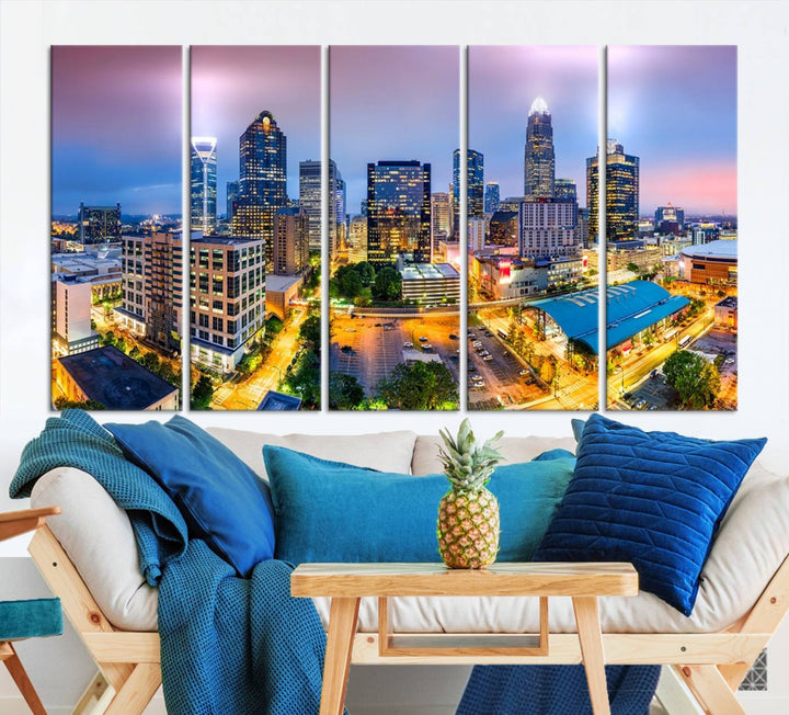 The living room features three large pieces of the *Charlotte City Lights Sunset Purple Skyline Cityscape View Wall Art Canvas Print*. Crafted on gallery-wrapped, museum-quality canvas with UV-protective coating, they grace the wall and add an artistic flair to the space.