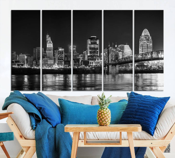 The Cincinnati City Lights Skyline Black and White Wall Art Cityscape Canvas Print elegantly adorns a modern living room. This museum-quality canvas triptych of a city skyline is enhanced by hand-assembled frames for added finesse, and you can enjoy free shipping on this stunning home addition.