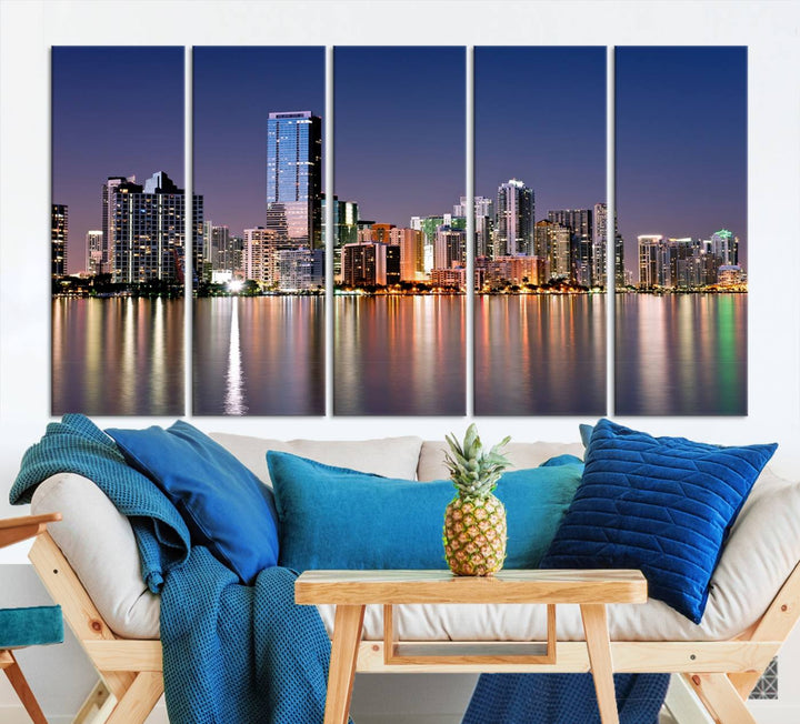 The Miami Skyline Canvas Wall Art Print showcases a vibrant night cityscape and beautifully captures the dazzling colorful lights reflecting on the water. This ready-to-hang triptych adorns the wall, creating a stunning visual centerpiece.