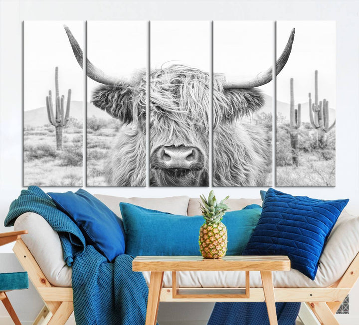 The "Rustic Charm | Cow Longhorn Black White Bighorn Wall Art Canvas Print" is a stunning triptych that showcases a highland cow with long horns set against a desert landscape with cacti in the background. This farmhouse wall art elevates any room into a rustic haven with its gallery-quality canvas.