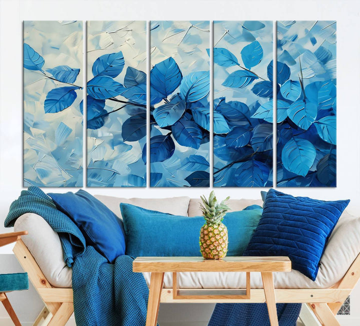 The contemporary living room is highlighted by the Abstract Blue Leaf Wall Art Canvas Print on the wall. The hand-assembled framed art enhances the room's vibrant decor, crafting a gallery-worthy ambience.