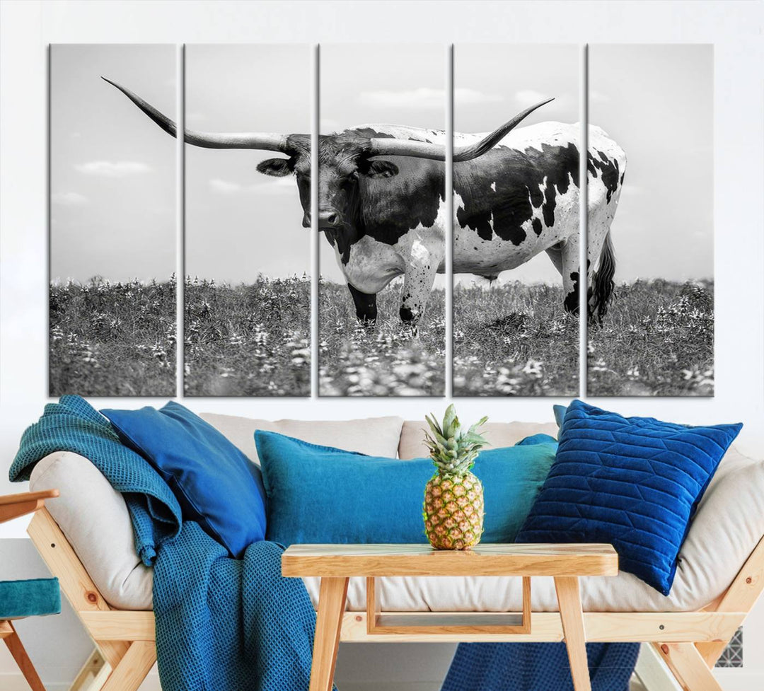 The Texas Black White Highland Longhorn Cow Wall Art Canvas Print, a gallery-quality triptych, elegantly adorns the wall, showcasing a striking black-and-white depiction of a longhorn cow in a field.