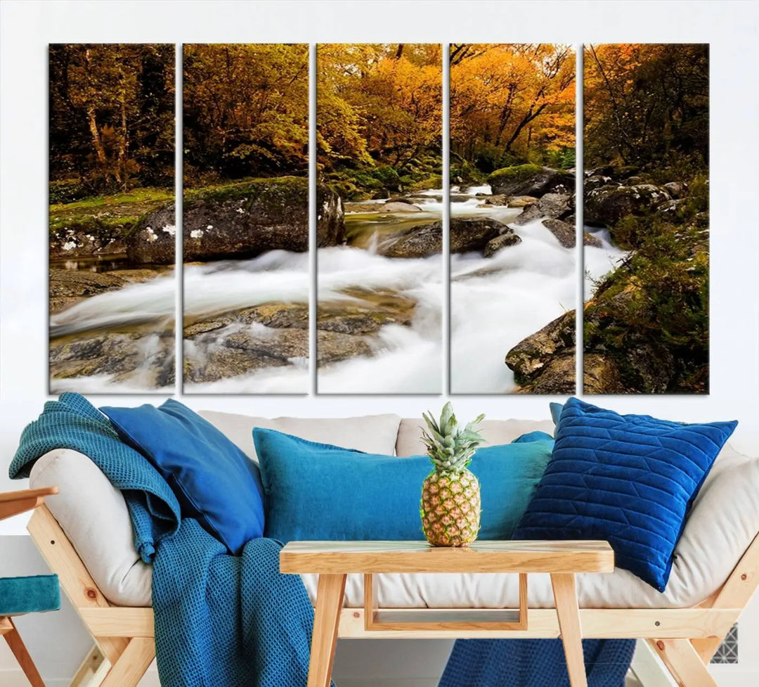 The living room is adorned with the "Wall Art Waterfall Canvas Print River in Forest in Autumn," a triptych on museum-quality canvas showcasing a flowing river surrounded by autumn trees. This ready-to-hang artwork features a UV-protective coating to ensure enduring vibrancy.