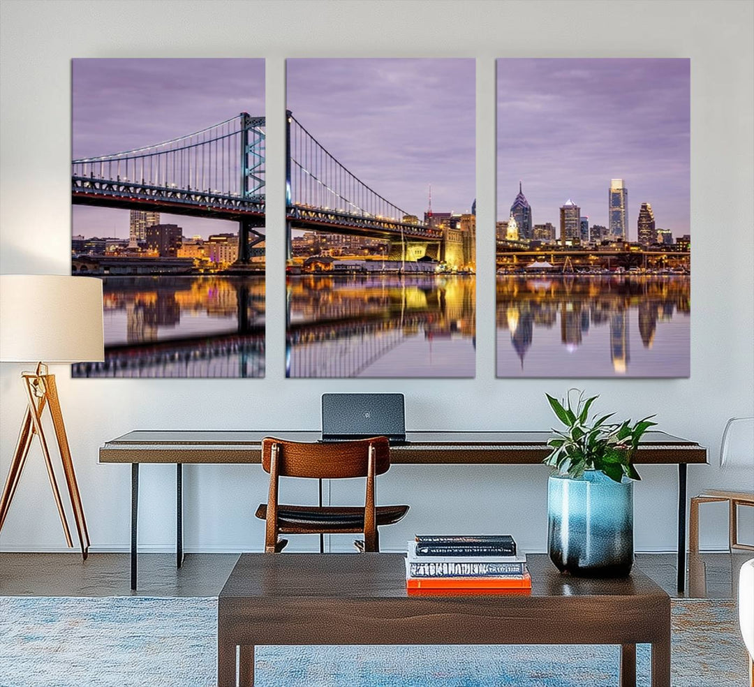 An Extra Large Wall Art Philadelphia Canvas Print, featuring a gallery-quality finish, captures the lit-up Ben Franklin Bridge and city buildings perfectly reflected on the water at sunset.