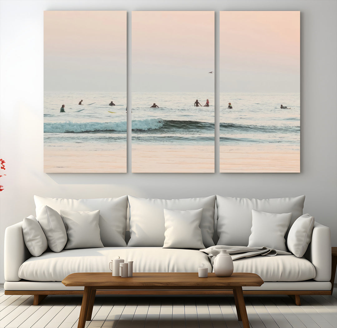 Dreamy photo of surfers waiting on soft pastel waves under a pink sunset sky, ideal for soft coastal minimalist or serene ocean-themed home decor.