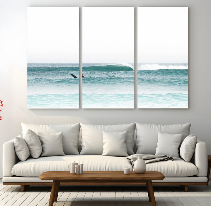 Minimalist photo of a lone surfer on calm aqua waves under bright sky, perfect for Scandinavian coastal or serene ocean-inspired home decor.