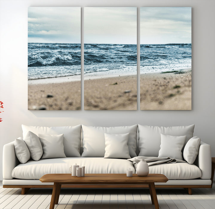 A moody ocean scene with gentle waves washing onto a sandy beach under a cloudy sky, creating a peaceful and coastal atmosphere.