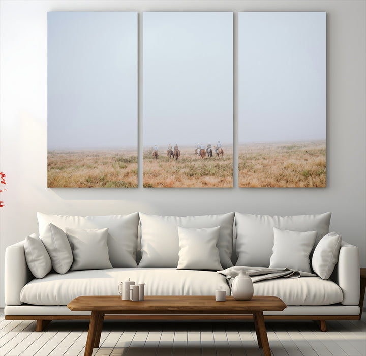 A group of horseback riders moving through a fog-shrouded field, evoking a calm Western scene with golden grasses and soft horizons.
