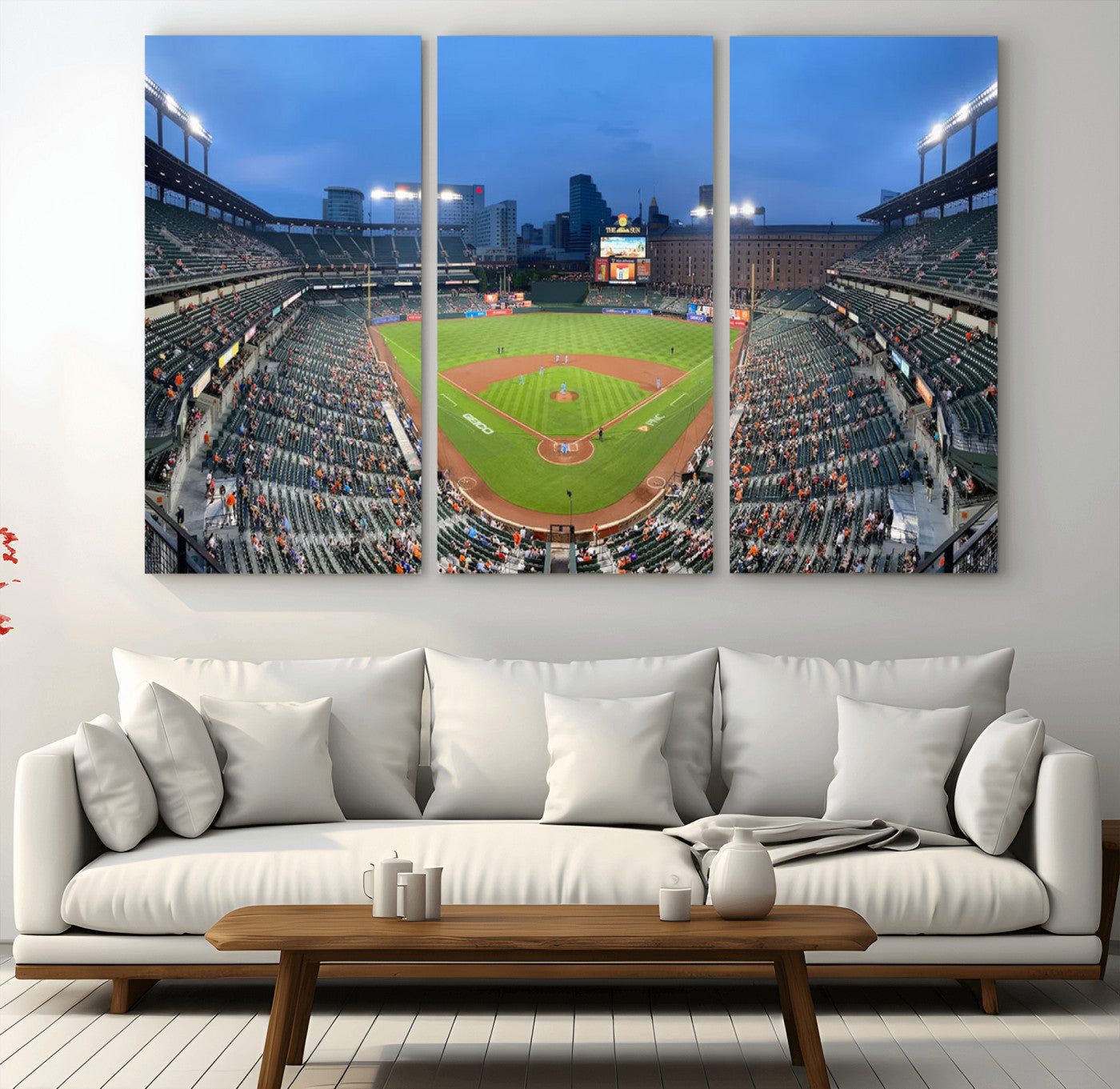 Wide panoramic view of a baseball stadium at dusk with players on the field, stadium lights illuminating the scene, and a sparse crowd of spectators in the stands.