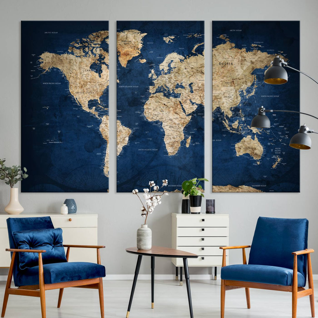 A large framed world map canvas print features beige landmasses set against a grunge-stained deep blue ocean background, creating an intriguing piece of wall art.