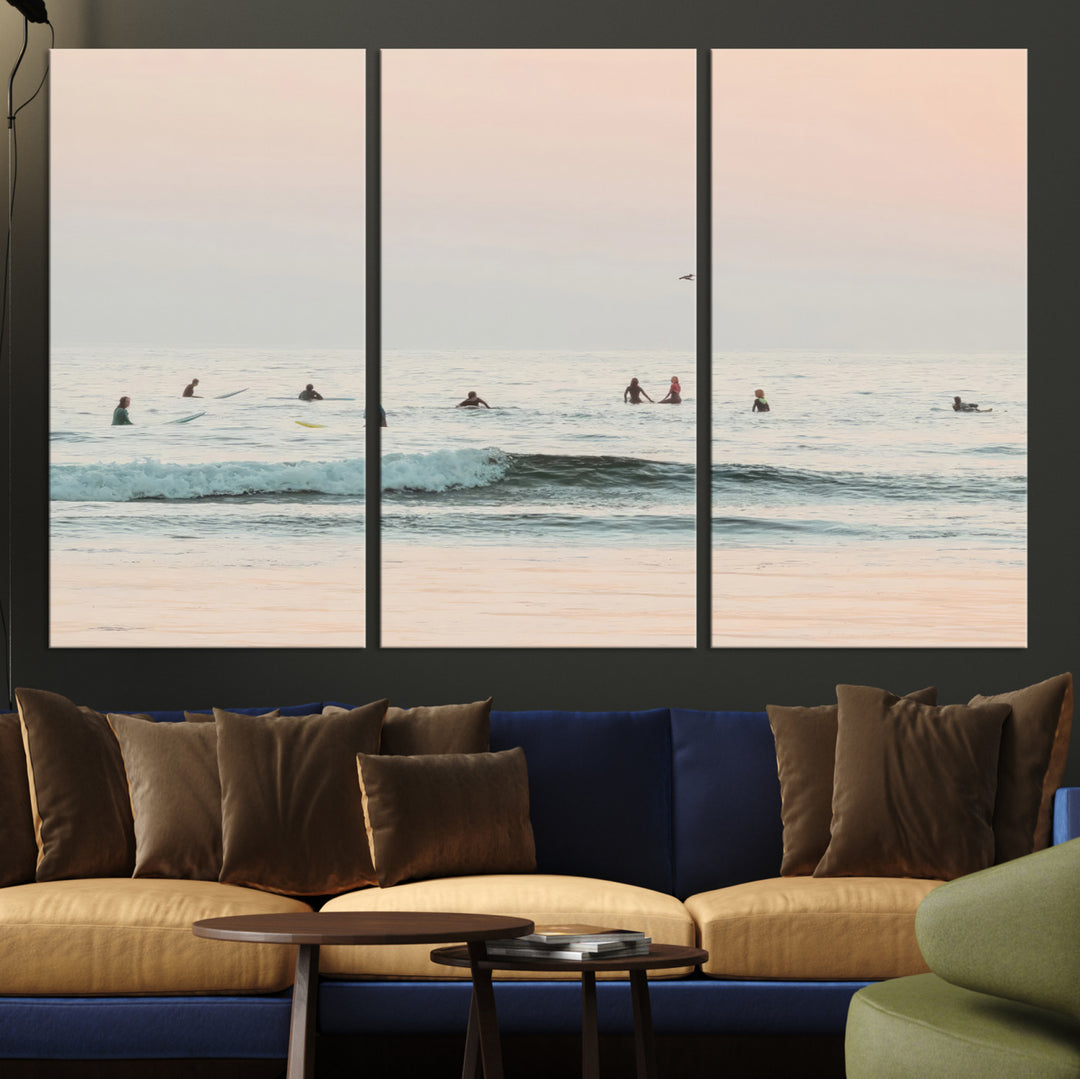 Dreamy photo of surfers waiting on soft pastel waves under a pink sunset sky, ideal for soft coastal minimalist or serene ocean-themed home decor.