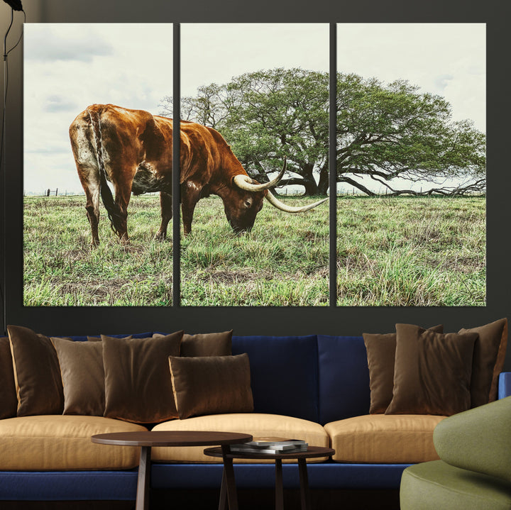 A Texas Longhorn grazing in a green pasture with a large tree in the background, evoking a rustic Western and farmhouse aesthetic.