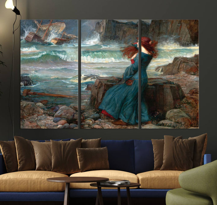 The Miranda by the Shore Wall Art Canvas Print depicts a woman in a blue dress standing by the sea, watching a shipwreck.