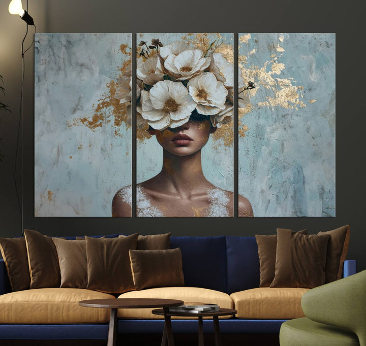 The Golden Petal Silhouette Woman Wall Art Canvas Print, a large 3-panel canvas with a textured gold floral design, serves as a luxurious centerpiece in modern glam settings. The artwork depicts a woman with flowers over her eyes against a textured background and hangs elegantly.