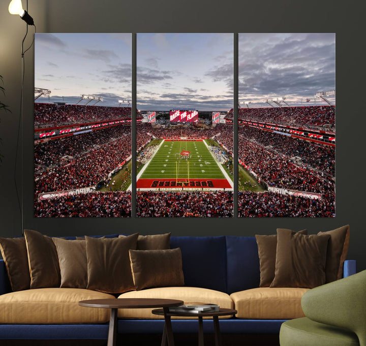 The wall art captures a stunning scene of Raymond James Stadium bathed in the warm hues of sunset. The sky, filled with clouds, provides a dramatic contrast to the vibrant lighting on the field, encapsulating the dynamic energy of a football game.