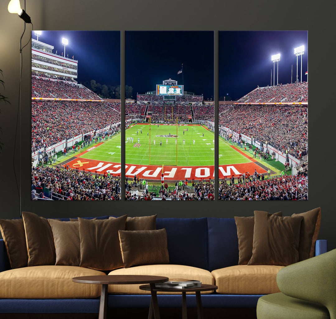 A NC State Wolfpack Football Team print of Carter-Finley Stadium at night features WOLFPACK illuminated brightly in the end zone grass.